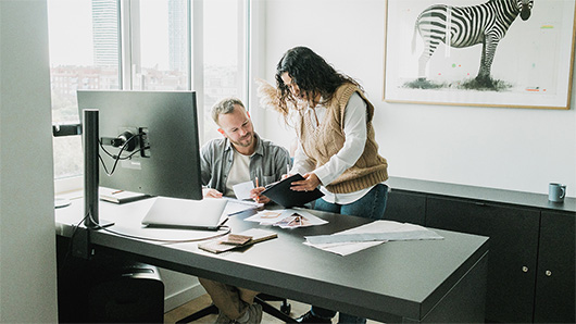 A couple reviewing papers together at a desk in a bright room