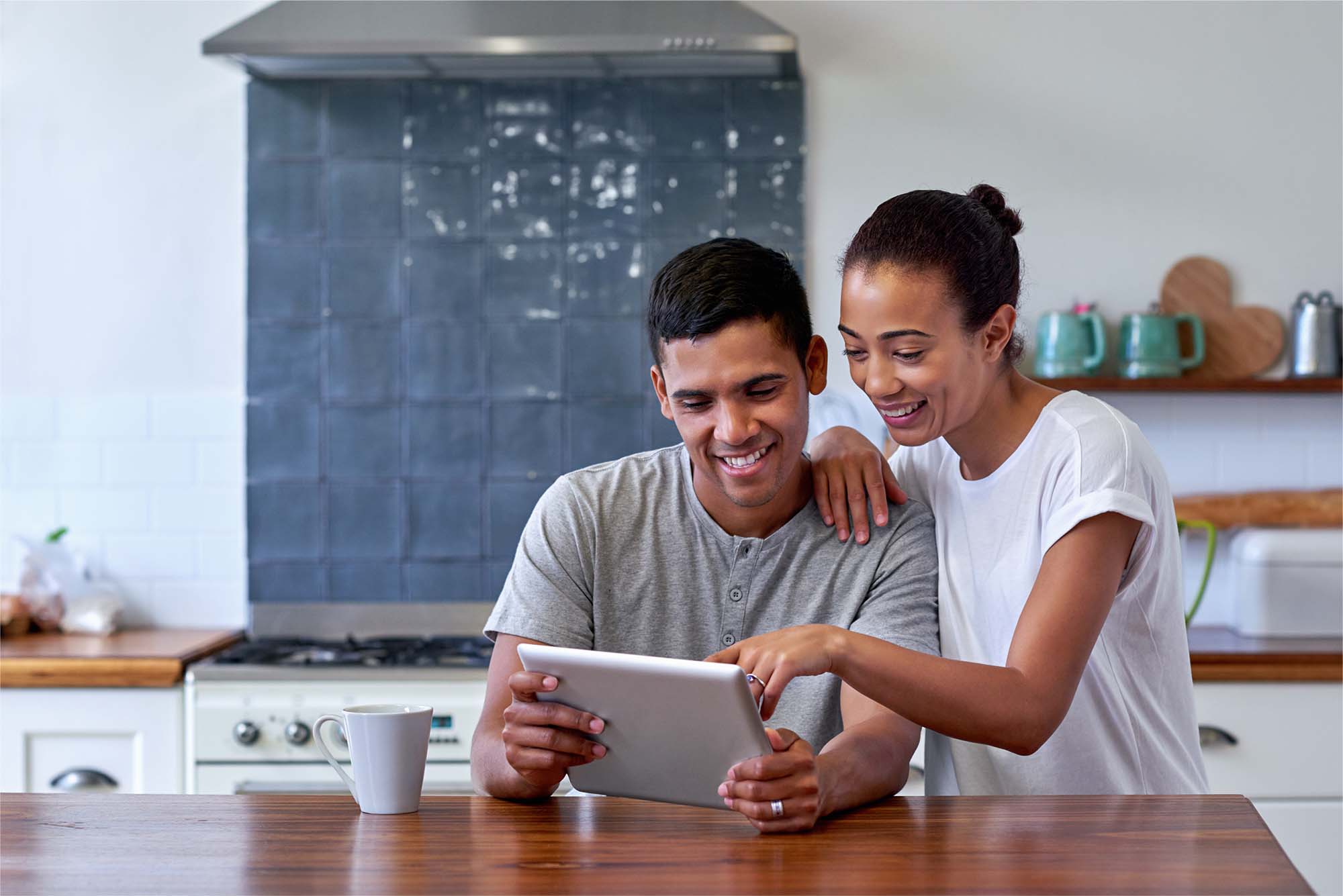 A smiling couple looking at a tablet together in their kitchen